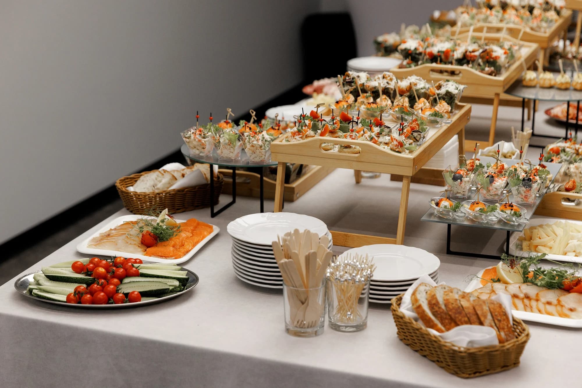 A long banquet table set with white linen, gold cutlery, black napkins and tall white floral arrangements