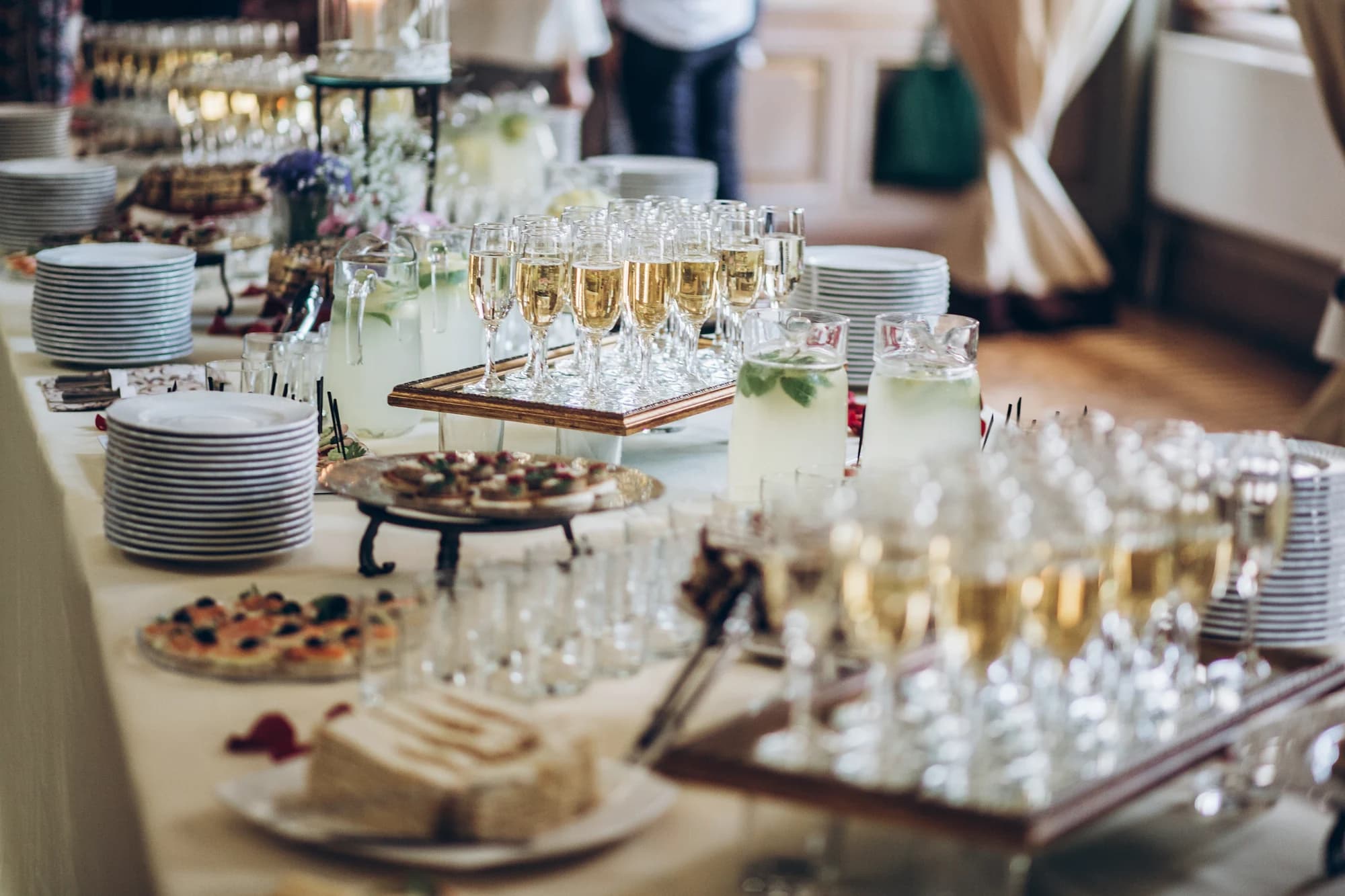 A guest taking a canapé from a buffet table dressed with flowers and platters